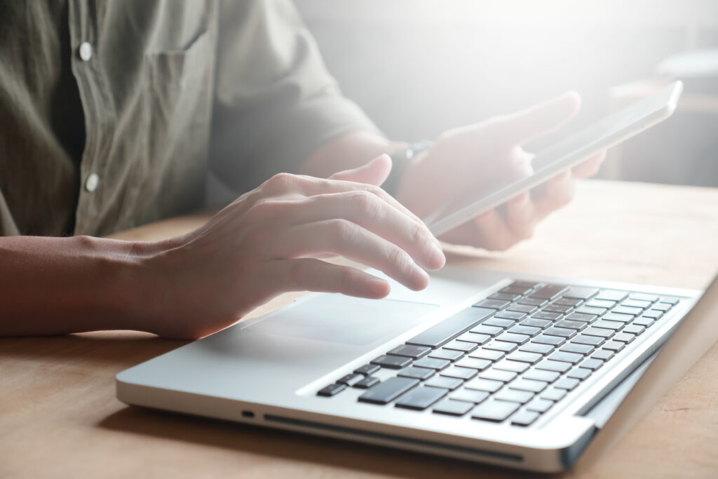Anmeldung close up of male hands using laptop and tablet on the table, ton